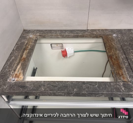 משטח שיש כהה עם חור מלבני במרכז